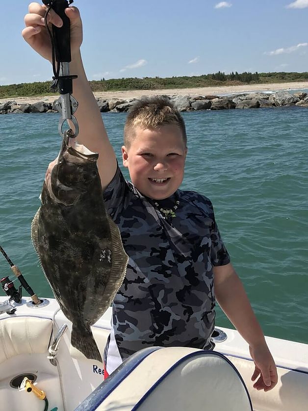 Young boy holds up fish caught on family trip
